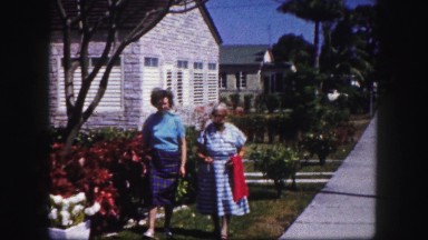 1960: two older women walking on beautiful street and talking about flowers