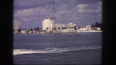 1960: panoramic view of an ocean resort with long bridge and tourist boat