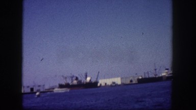 1960: ships and large structures on the surface of large blue body of water.