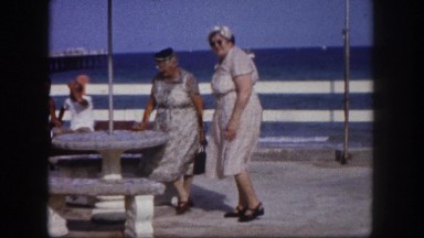 1960: two older women on sunny day outdoor sitting at cement table