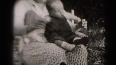 1947: woman holds closely small baby on her lap as it smiles. MIDDLETOWN