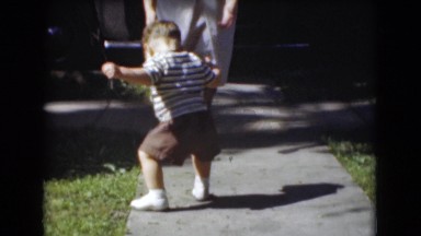 1947: exploring toddler falls and mother in white dress stands