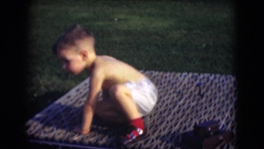 1947: baby toddler boy sitting on outdoor picnic blanket on hot summer day
