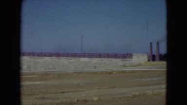 1947: car is parked by ramp while ship is docked and river flows under bridge