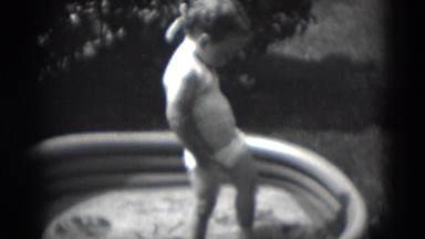 1949: black and white footage of toddler in the yard standing in kiddie pool