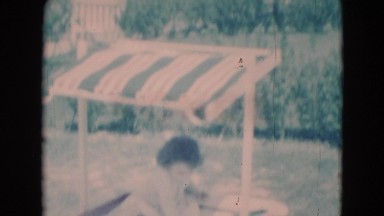 1949: little girl playing in fancy sandbox with shade structure