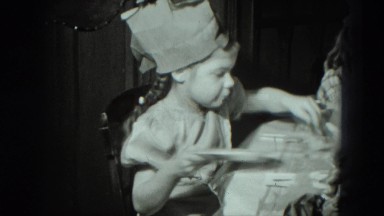 1951: at small dining table, small girls play and unwrap gifts. GERMANY