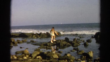 1966: lady walking on rocks near the ocean CALIFORNIA