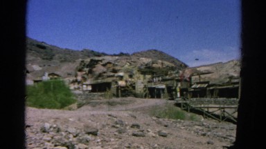 1966: abandoned western mining town with buildings set against rocky hillside