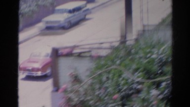 1966: red car drives down empty street on clear and windy day CALIFORNIA