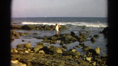 1966: woman wading through the rocky water on the coast CALIFORNIA