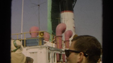 1966: man on cruise ship watching dark black smoke from ship exhaust system