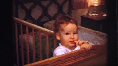 1973: Shy and Beautiful Child Standing on Cradle in Bedroom, Lynbrook