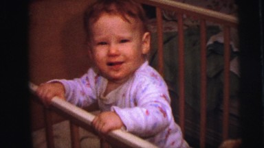 1973: cute redhead baby boy in crib reaching around grabbing at things.