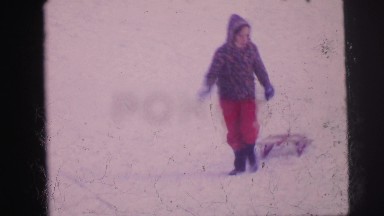 1974: little girl is pulling sled down snowy hill. LYNBROOK, NEW YORK