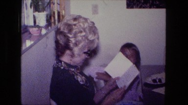 1976: middle aged women with blonde curly hair opening birthday card gift
