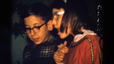 1968: eyeglasses wearing borther and sister at christmas singing carols
