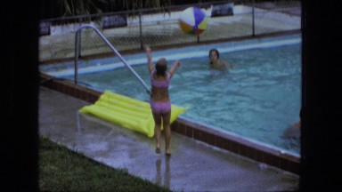 1976: young caucasian girls playing in swimming pool bikinis lawn chairs