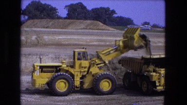1976: earth mover is pouring soil into the cabin of truck FORT WAYNE, INDIANA