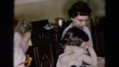 1957: five members of family sitting around the table enjoying meal together