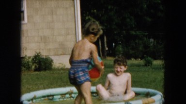 1957: during the day young boy with swim trunks jumps into an inflatable pool
