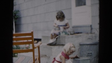 1957: two little girls playing house in their yard by cement steps