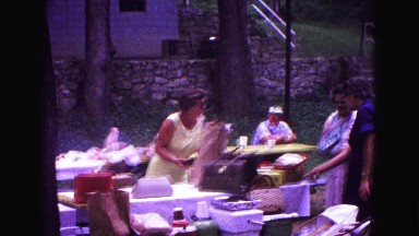 1971: adult women and men with some children in public park at picnic table