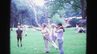 1971: middle-aged woman and older woman take turns throwing large darts in park