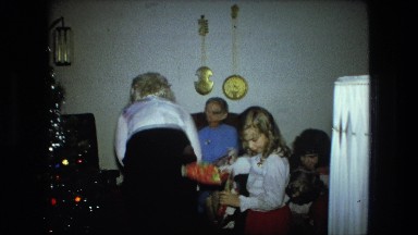 1974: lady in black skirt is handing gifts which were under christmas tree
