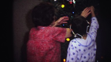 1973: grandmother and granddaughter decorating christmas tree together LYNBROOK
