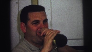 1973: gentleman, while laughing, pretends to take drink out of bottle in front