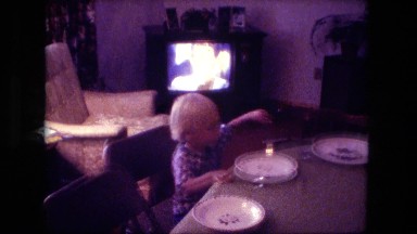 1974: blonde caucasian boy watching tv eating lunch at kitchen counter table