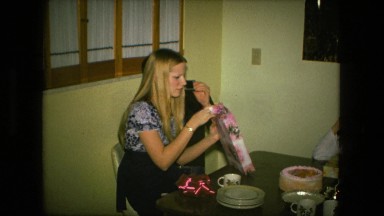 1974: beautiful couple sitting at table and unpacking present FORT WAYNE