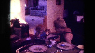 1974: young mother sitting at table feeding her baby in high chair FORT WAYNE