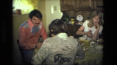 1974: group of friends and family sit on small table as they drink tea