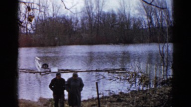1960: elderly couple walking from the shore of lake at sunset in the winter