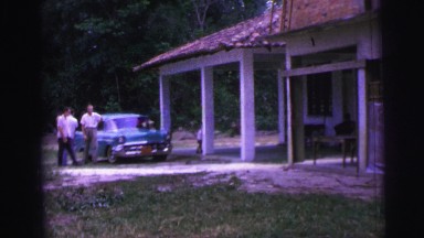 1967: people walking away from classic vehicle toward structure