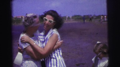 1967: younger woman greets older woman at airport before helping with bags