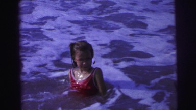 1967: young white girl swimming in ocean beach water foamy frothy waters BRAZIL