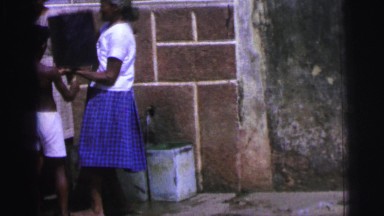 1967: woman is helping to little boy to put gallon of water on top of his head