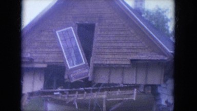 1965: excavator pushing top story and roof down on damaged house WAUPACA