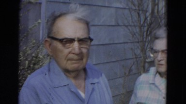 1967: an older man and woman with glasses outdoor on windy day talking. LINCOLN