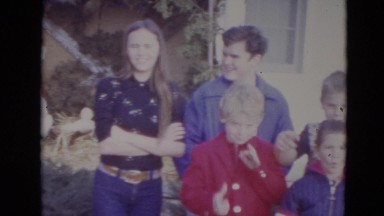 1974: large family of happy children standing in front of brick home LINCOLN