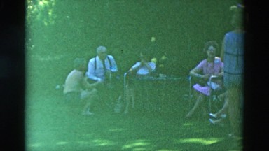 1958: group of old friends sitting outdoor talking and enjoying small party.