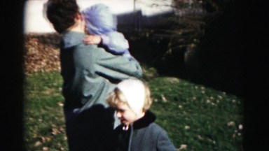1962: sister trying to get mothers attention holding baby on cold winter day
