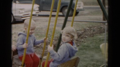 1962: blonde twin siblings playing on seesaw teeter totter playground swing