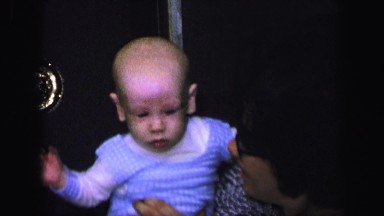 1972: young mother with eyeglasses bouncing her baby in her lap LYNBROOK