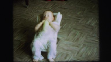 1972: baby with bottle in bouncing seat LYNBROOK, NEW YORK