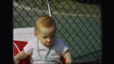 1972: excited toddler trying to escape baby seat. LYNBROOK, NEW YORK