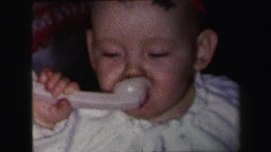 1972: cute chubby baby boy eating breakfast spoon LYNBROOK, NEW YORK
